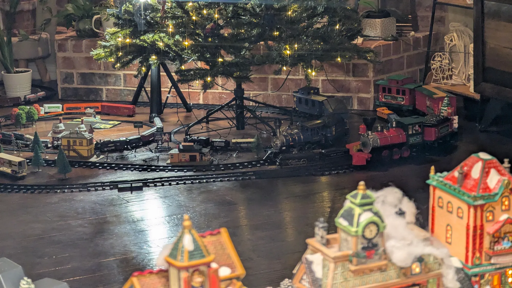 Model trains running on track beneath a Christmas tree