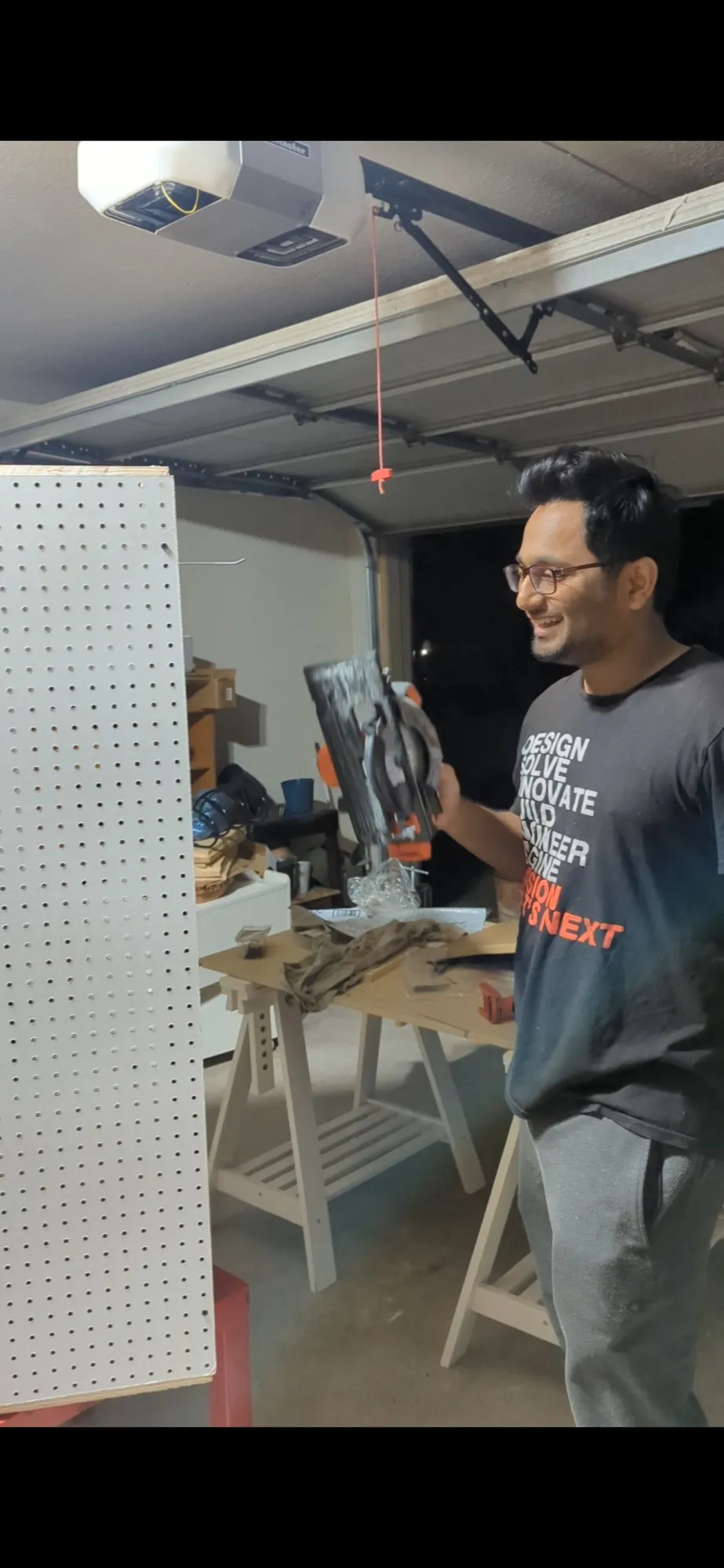 Varun Singh holding a circular saw in his garage workshop